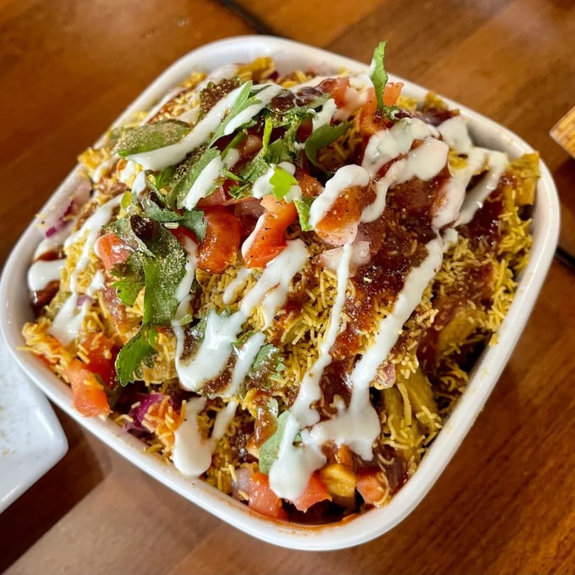Aroma Indian Palace's Indian street food, a colorful chaat dish with sauces, tomatoes, and cilantro.