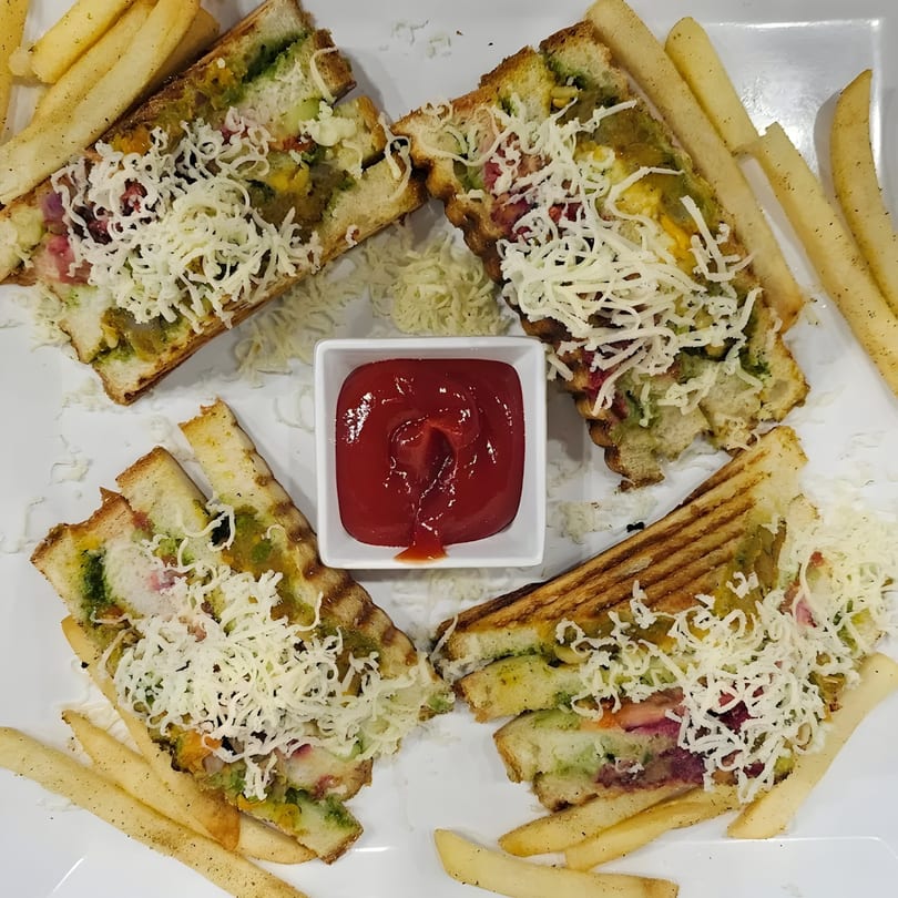 Four grilled sandwiches with green chutney, cheese, and fries, served with ketchup.