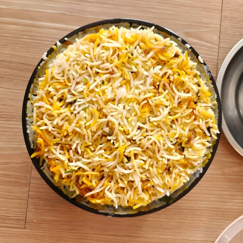 Aroma Indian Palace's chicken biryani, a flavorful rice dish with spices and chicken, served in a black bowl.